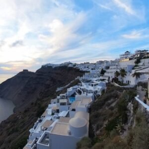 Sunset view of Oia village with white houses and blue domes on the caldera cliffs, featured in the Santorini virtual tour.